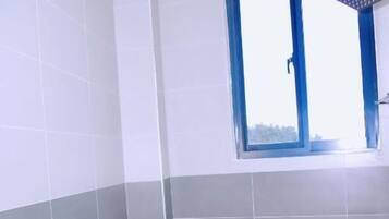 A bathroom with a toilet, a shower, and a window.