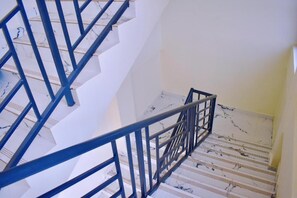 Una escalera con barandilla de metal azul y paredes blancas.