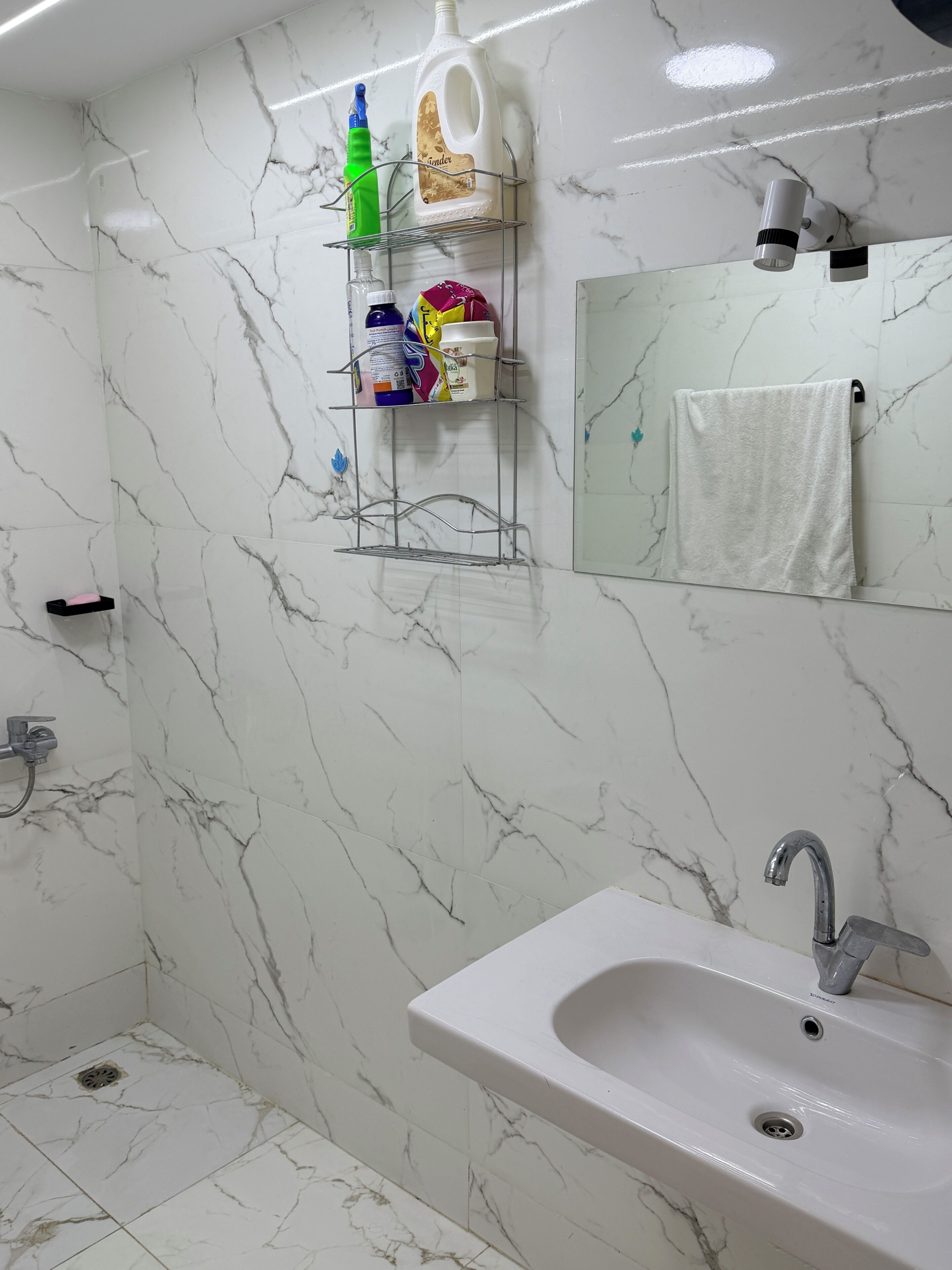 Ein Badezimmer mit einem weißen Waschbecken, einem Spiegel und einem Handtuchhalter.