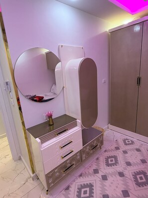 Een kamer met een kaptafel, spiegel, kledingkast en vloer met patroon.