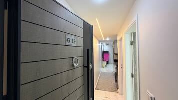 A hallway with a door labeled 'G 12' leading to a room with a tiled floor.