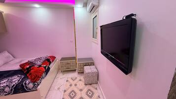 A bedroom with a bed, a television, a wardrobe, and a patterned floor.