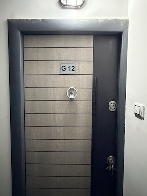 Een deur met een metalen plaatje met de tekst 'G 12' en een sleutelgat.