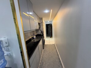 Eine moderne Küche mit schwarzem Arbeitsplatz, weißen Schränken und einer Marmor-Spritzschutzwand.