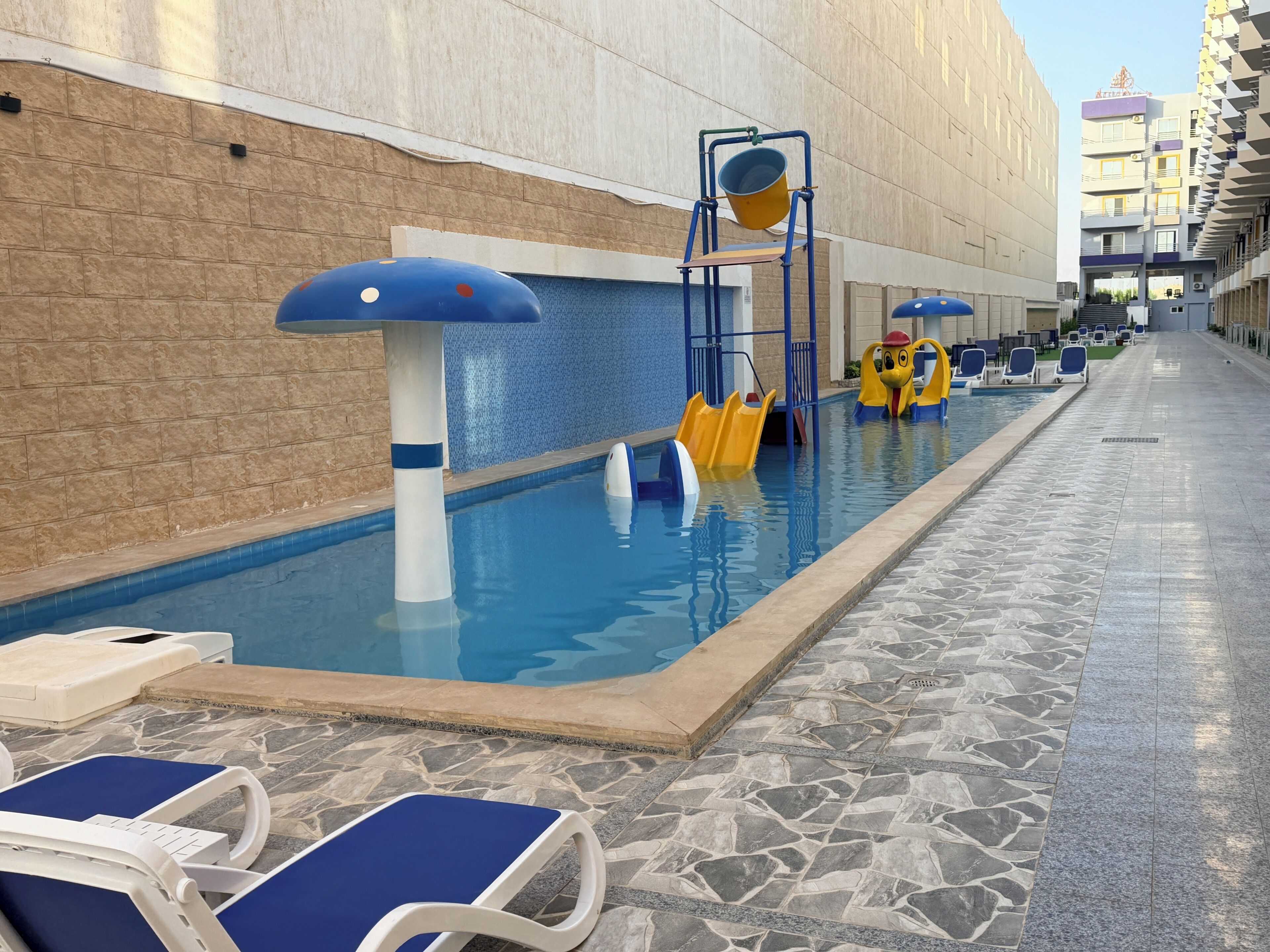 Ein Schwimmbecken mit Wasserrutschen und Liegestühlen.