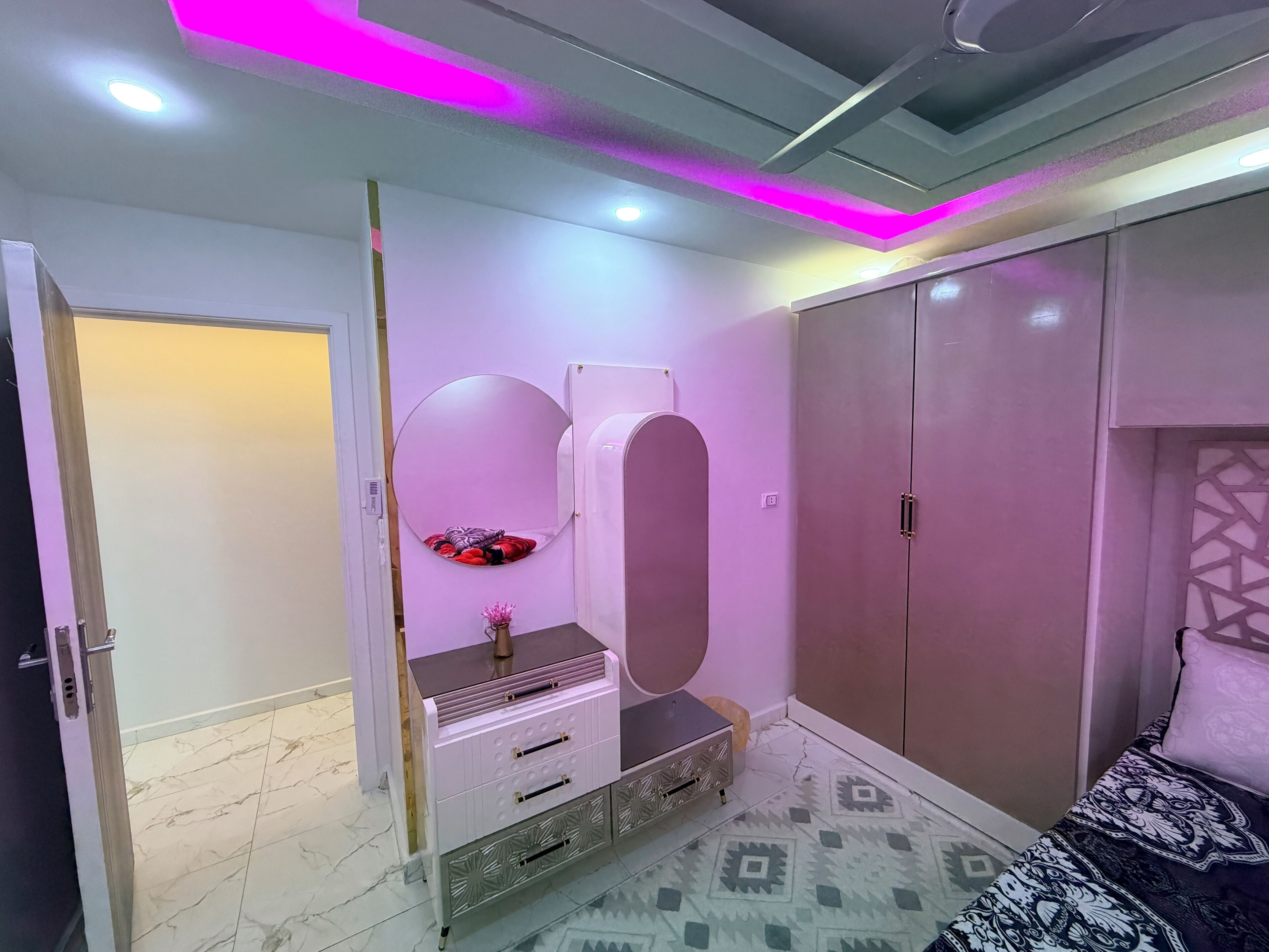 Un dormitorio con armario, tocador con espejo y cama con ropa de cama estampada.