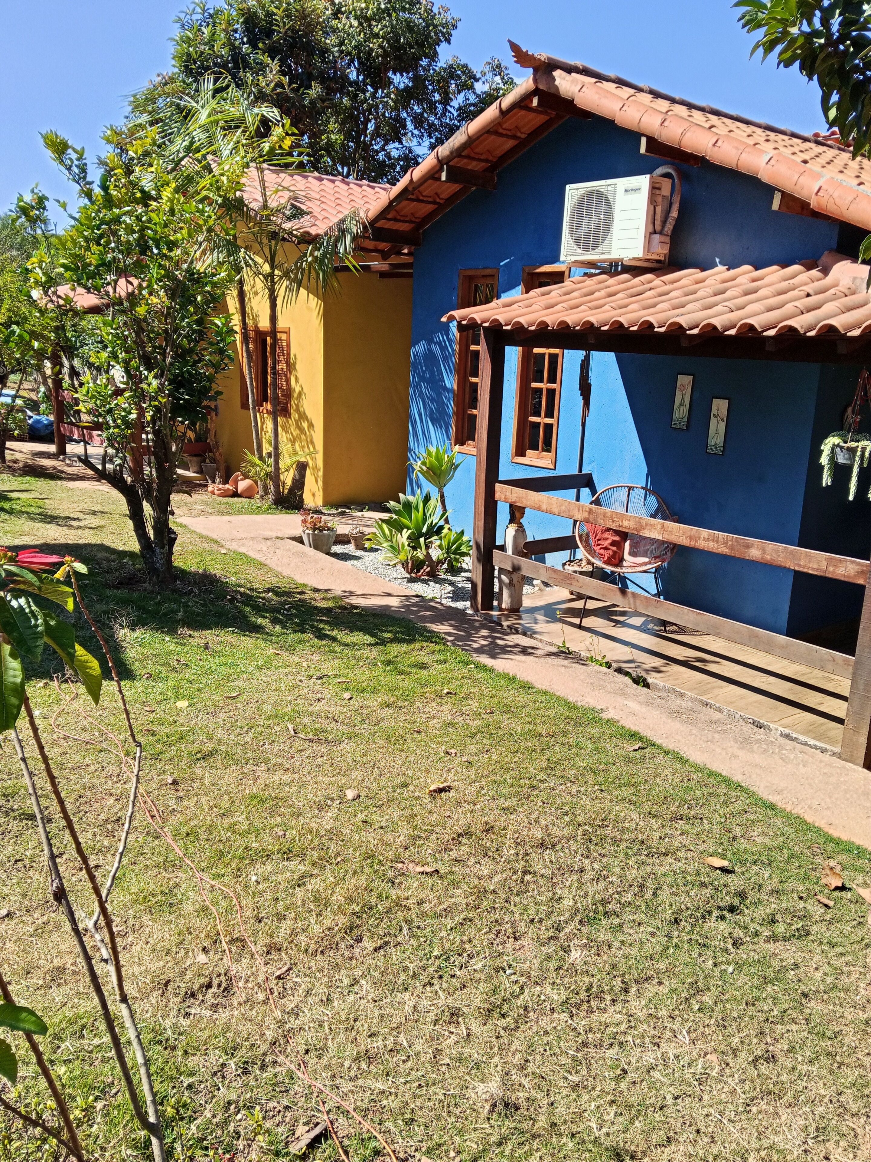 A residential area with a blue house featuring a tiled roof, a wooden fence, and a hammock.