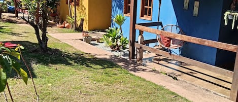 A residential area with a blue house featuring a tiled roof, a wooden fence, and a hammock.