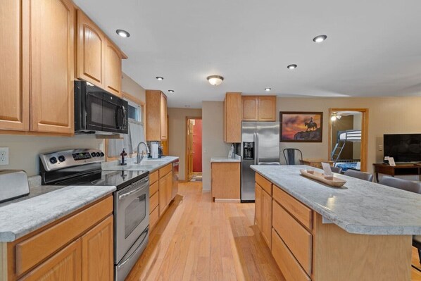 A modern kitchen with wooden cabinets, stainless steel appliances, and a marble countertop.