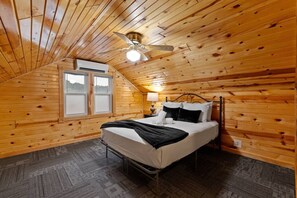 Ein Schlafzimmer mit einem Bett, einem Deckenventilator, einer Klimaanlage und einem Fenster.