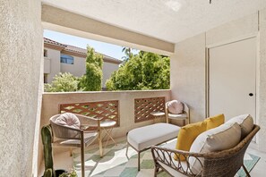 A balcony with wicker furniture, a white door, and a view of buildings and trees. - Hummingbird Hideaway - Executive Resort-style Condo (Phoenix)