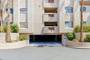 A multi-story building with a parking garage entrance, palm trees, and a sign indicating 'CLEARANCE 7' for parking. - Hummingbird Hideaway - Executive Resort-style Condo (Phoenix)