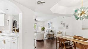 A modern kitchen with white cabinetry, a wooden dining table, and a chandelier. - Hummingbird Hideaway - Executive Resort-style Condo (Phoenix)