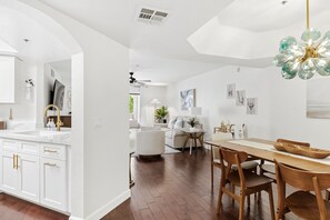 A modern kitchen with white cabinetry, a wooden dining table, and a chandelier. - Hummingbird Hideaway - Executive Resort-style Condo (Phoenix)