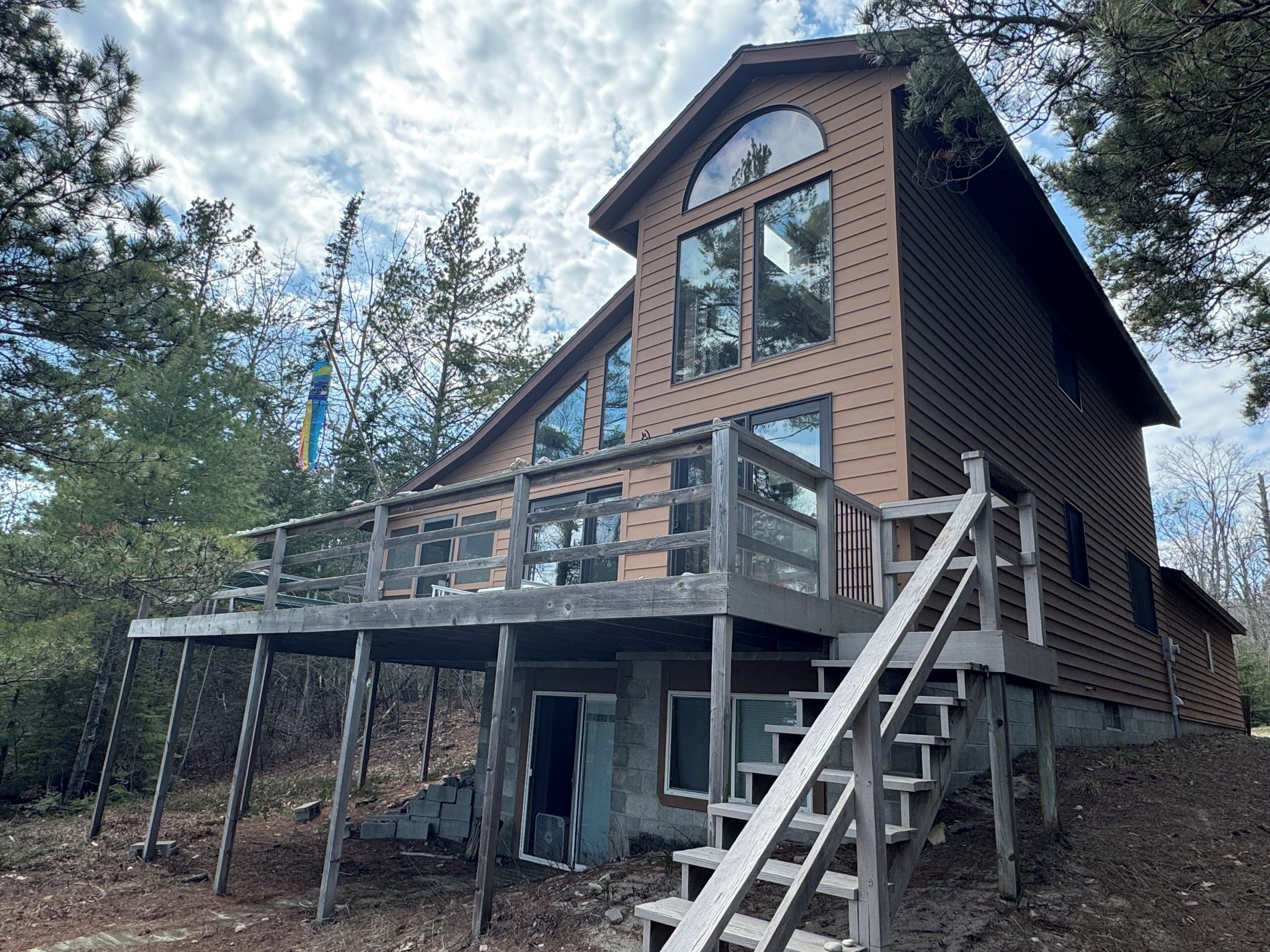 Eine zweistöckige Holzhütte mit einem Balkon und einer Treppe, die zum Obergeschoss führt.
