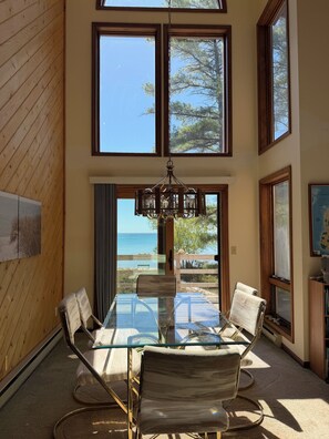 En matplats med ett glasbord och stolar, stora fönster och utsikt över havet.