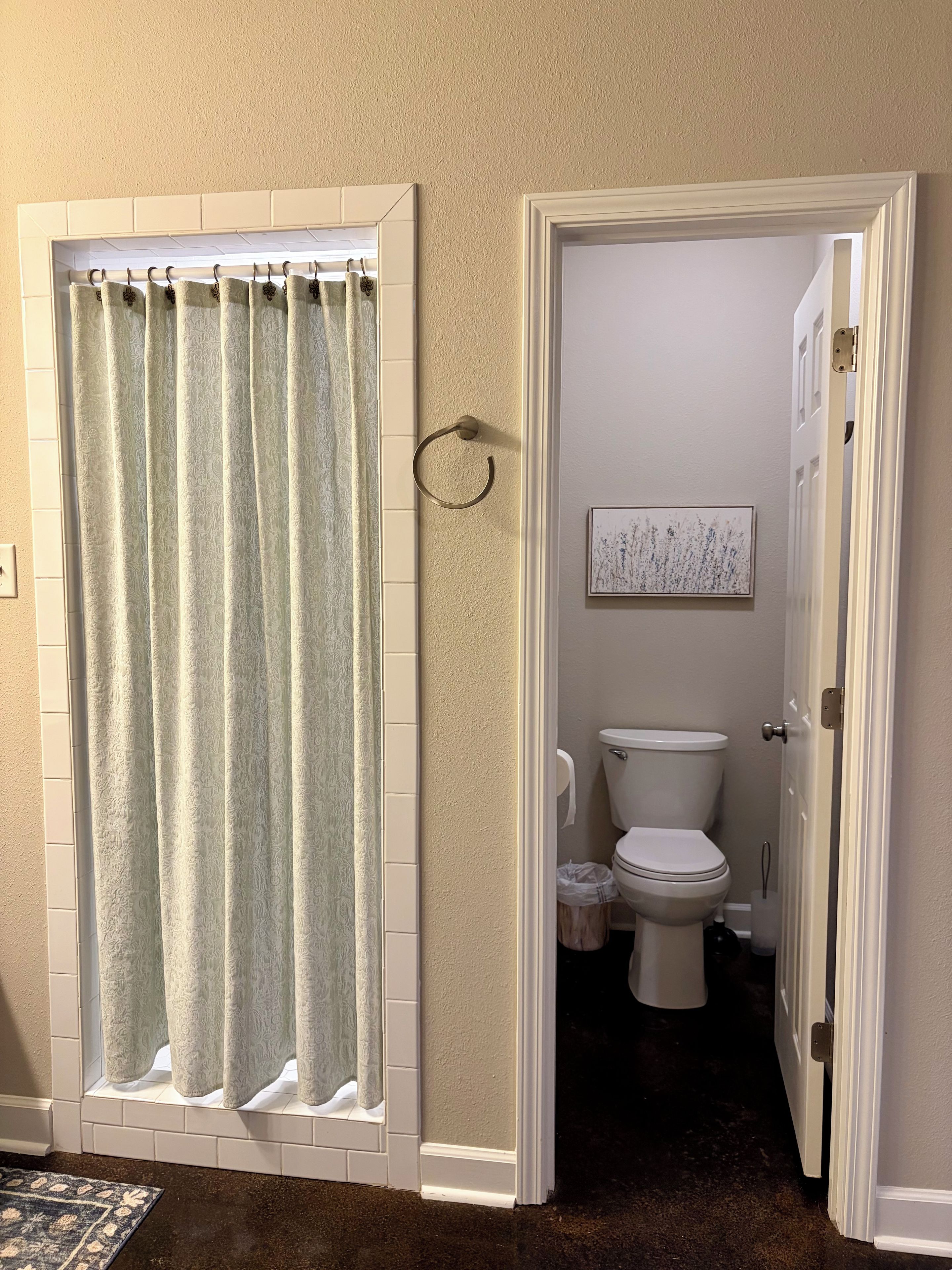 Ein Badezimmer mit Toilette, Handtuchhalter und einer Tür zu einem anderen Raum.