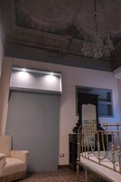 Una habitación con cama, una silla, un espejo y una araña.