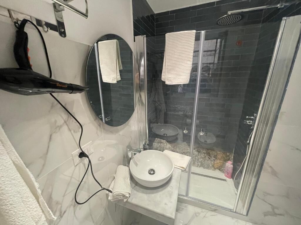 Un bagno con doccia in vetro, un lavandino bianco e uno specchio.