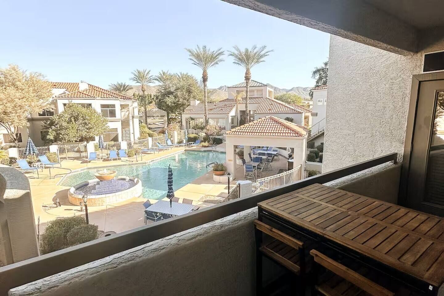 A pool area with lounge chairs and a gazebo, surrounded by buildings with a Mediterranean architectural style.