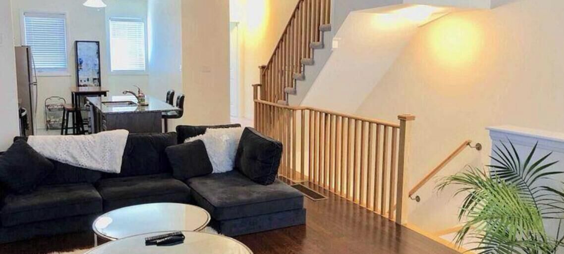 A modern living room with a sectional sofa, a coffee table, and a staircase leading to an upper level.