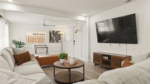 Een moderne woonkamer met een bank, salontafel en een flatscreen televisie aan de muur.