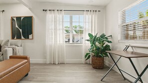A room with a sofa, a table, a potted plant, and a window with curtains. - Tampa Family Home with Putting Green + Fenced Yard (Tampa)