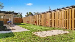 A backyard with a wooden fence, a patio, and a small lawn. - Tampa Family Home with Putting Green + Fenced Yard (Tampa)
