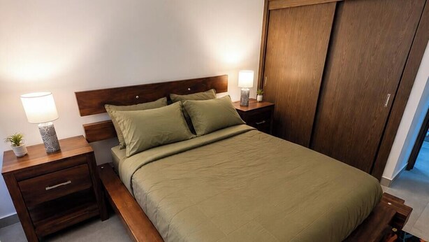 A bedroom with a bed, nightstands, a lamp, a wooden wardrobe, and a potted plant. - ANYA 6 Downtown Bayahíbe Retreat Pool  (Bayahíbe)