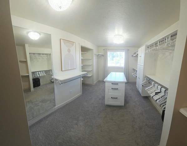 A walk-in closet with mirrored doors, a vanity with a mirror, and multiple storage shelves.