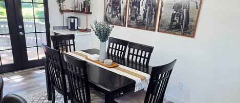 A dining area with a black table, chairs, a chandelier, and framed pictures on the wall.