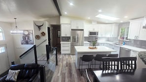 A modern kitchen with white cabinets, stainless steel appliances, and a central island with bar stools.