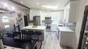 A modern kitchen with white cabinetry, stainless steel appliances, and a central island with bar stools.