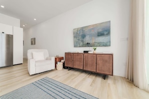 Ein modernes Wohnzimmer mit einem weißen Sofa, einem Korbtisch und einem großen abstrakten Gemälde an der Wand.