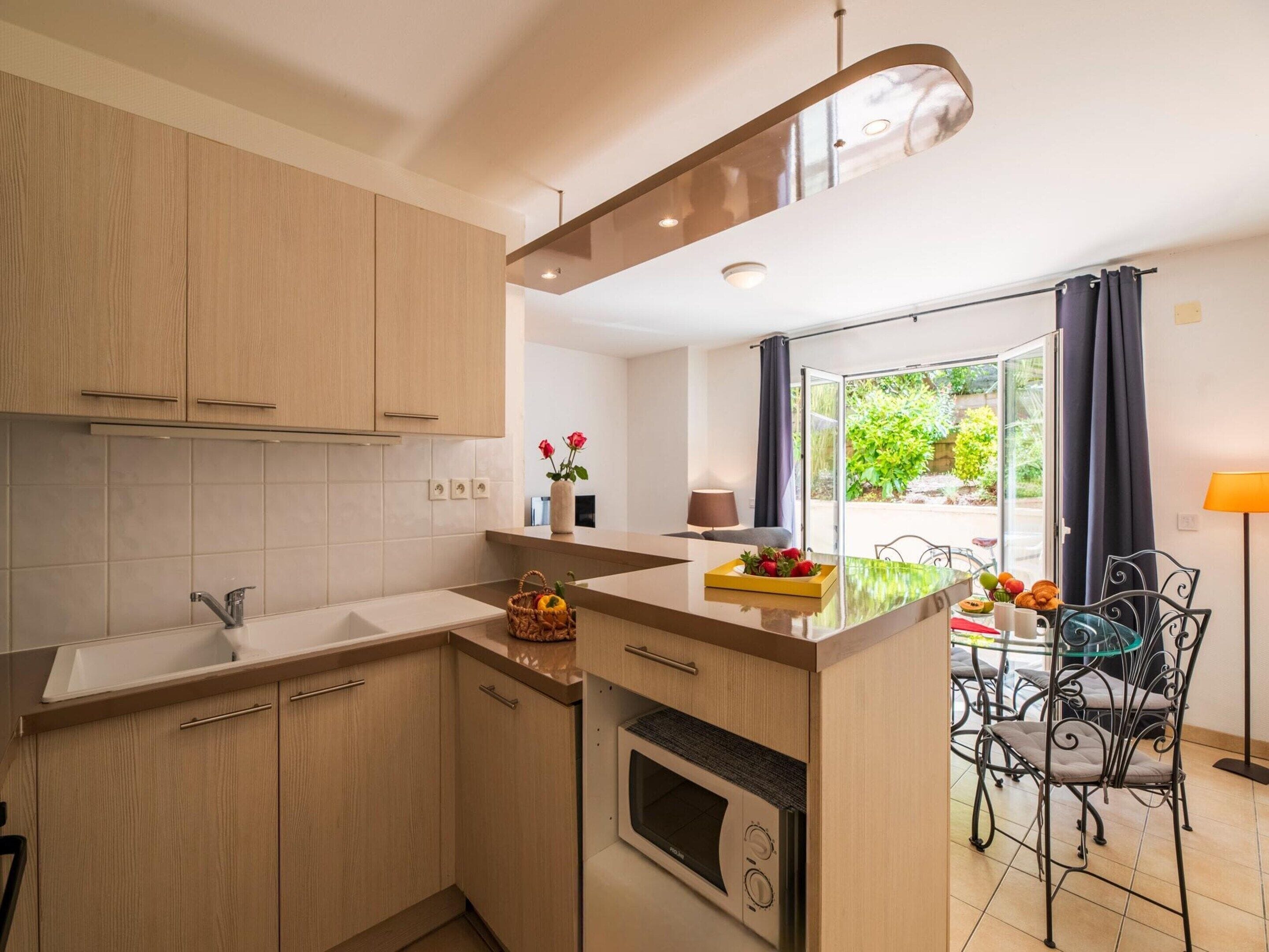 Una cocina moderna con armarios de madera, horno empotrado y un comedor con mesa y sillas.