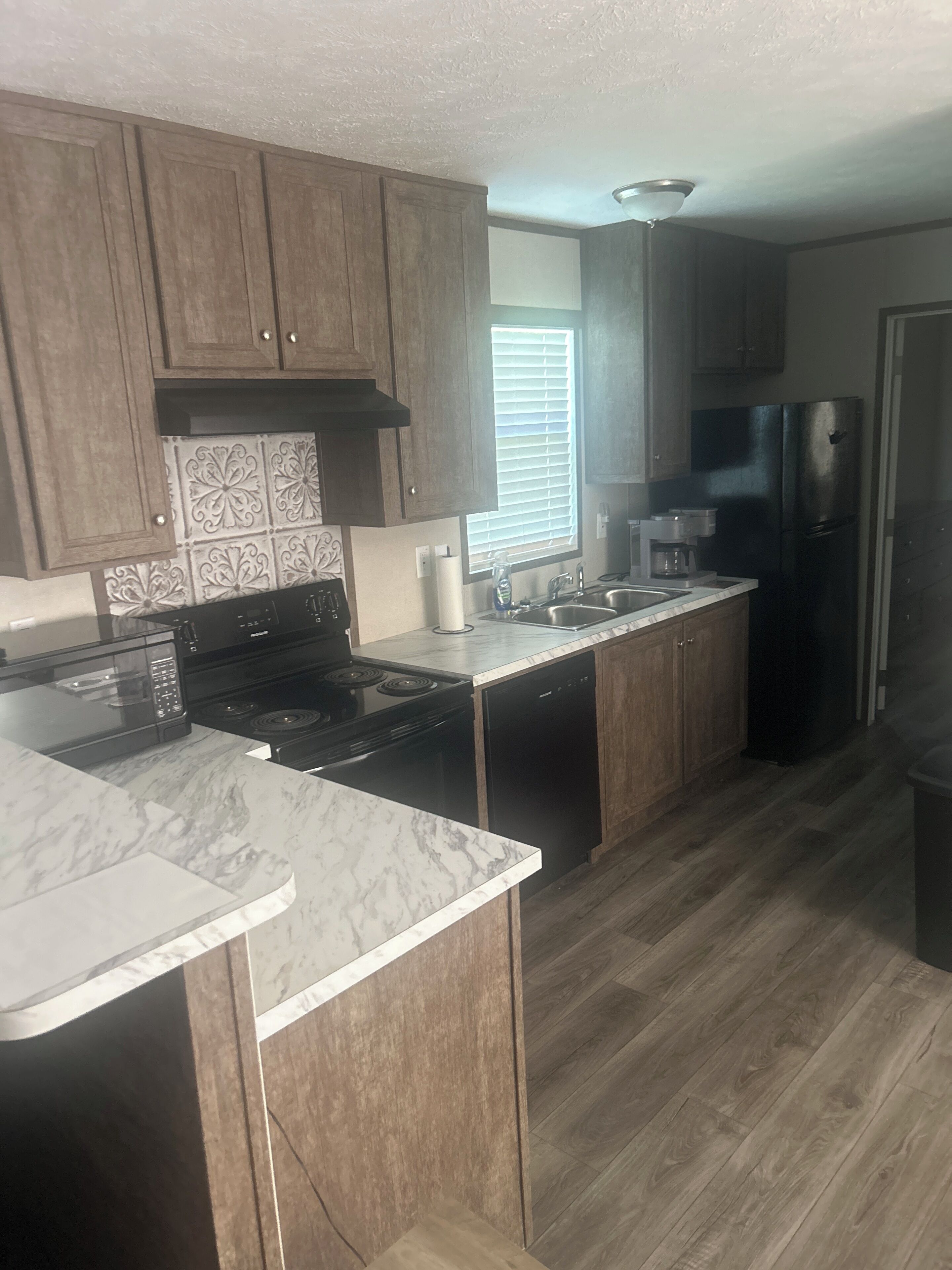 A kitchen with wooden cabinets, a stainless steel refrigerator, a microwave, and a dishwasher.