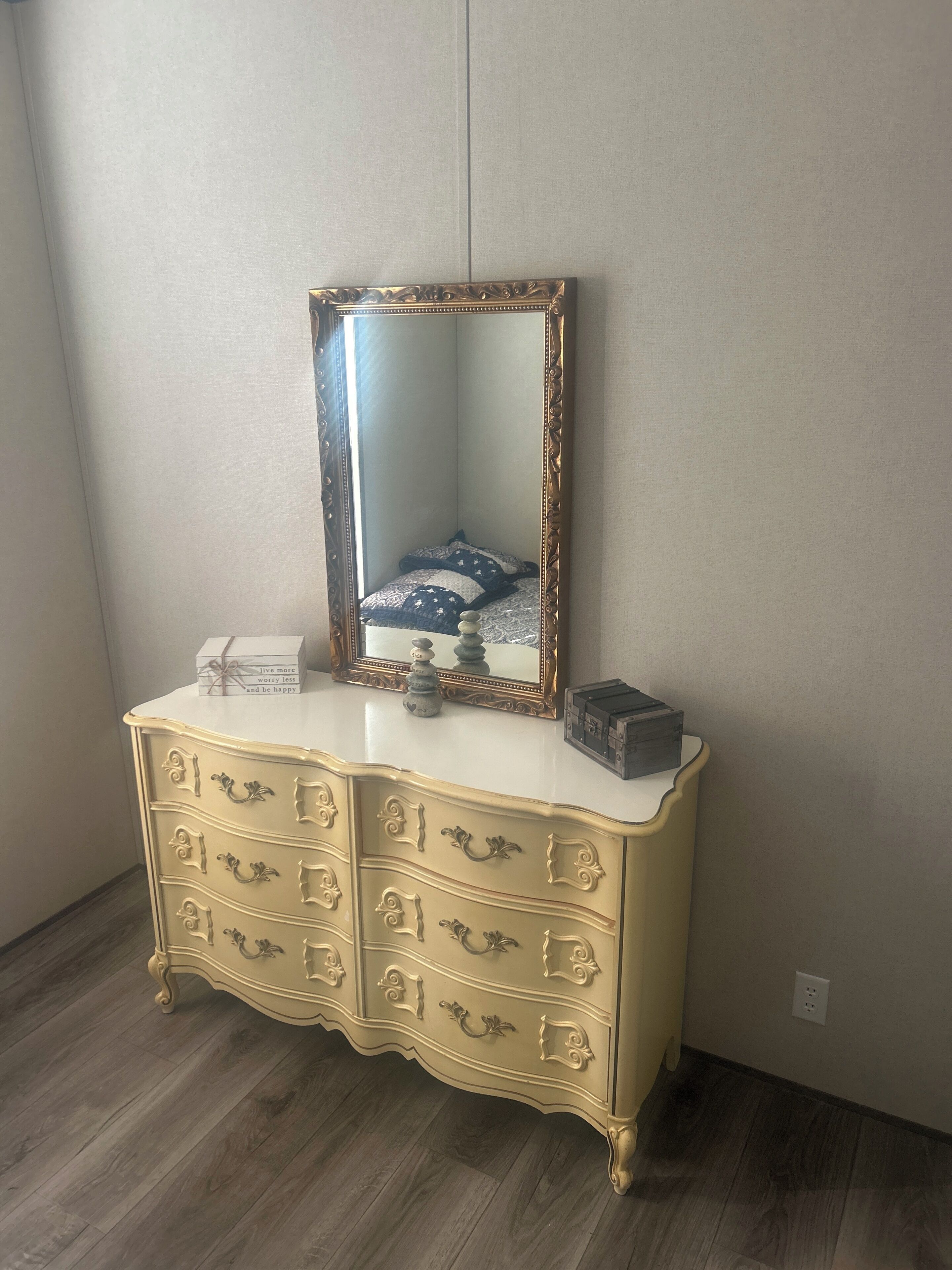 A dresser with a mirror and a box on top.