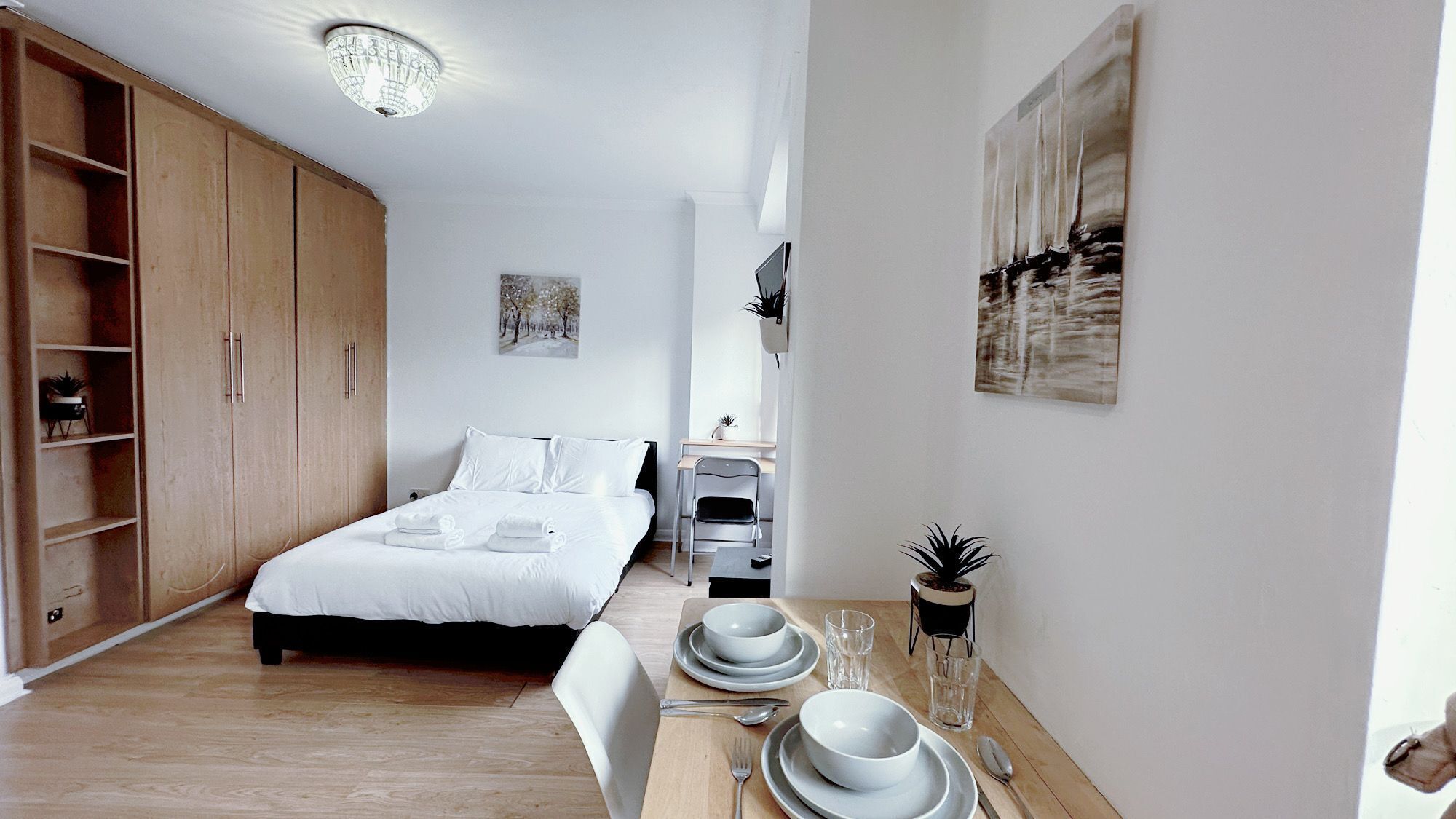 Un dormitorio con cama, un escritorio y una mesa de comedor con platos y vasos.