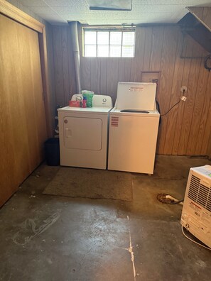A laundry room with a washing machine, dryer, and a small window.