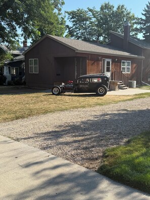 A vintage car parked in front of a wooden house with a garage.