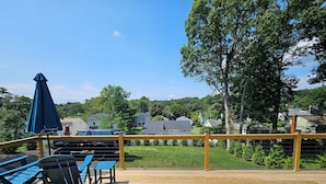 A wooden deck with outdoor furniture, a view of houses, and a clear sky.