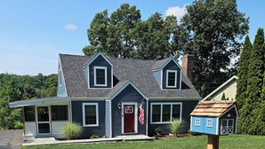 A two-story house with a red door, a covered porch, and a mailbox.