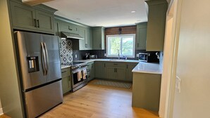 A modern kitchen with a stainless steel refrigerator, built-in oven, and microwave.