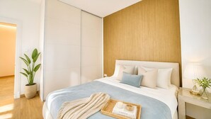 Ein modernes Schlafzimmer mit Bett, Nachttisch, Lampe und einem Topfpflanzen.