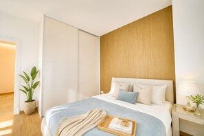 Ein modernes Schlafzimmer mit Bett, Nachttisch, Lampe und einem Topfpflanzen.