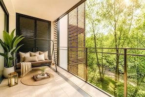A balcony with a sofa, a potted plant, and a view of a green landscape. - Old Town Heart XV - TOP Luxury Grzybowska 104m2 (Warszawa)