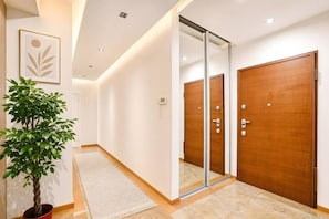 A hallway with a potted plant, a framed artwork, and a sliding glass door leading to a room. - Old Town Heart XV - TOP Luxury Grzybowska 104m2 (Warszawa)
