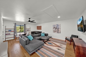 A modern living room with a sectional sofa, a dining table, and a flat-screen TV mounted on the wall. - The King Ranch I South Fork, Colorado Retreat (South Fork)