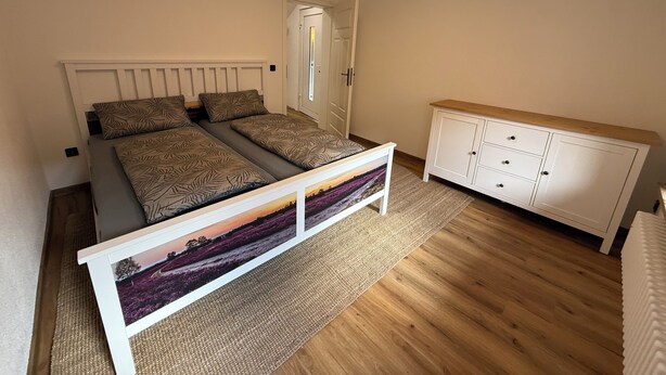 Ein Schlafzimmer mit einem Bett, einem Kleiderschrank und einem gerahmten Bild auf dem Boden.