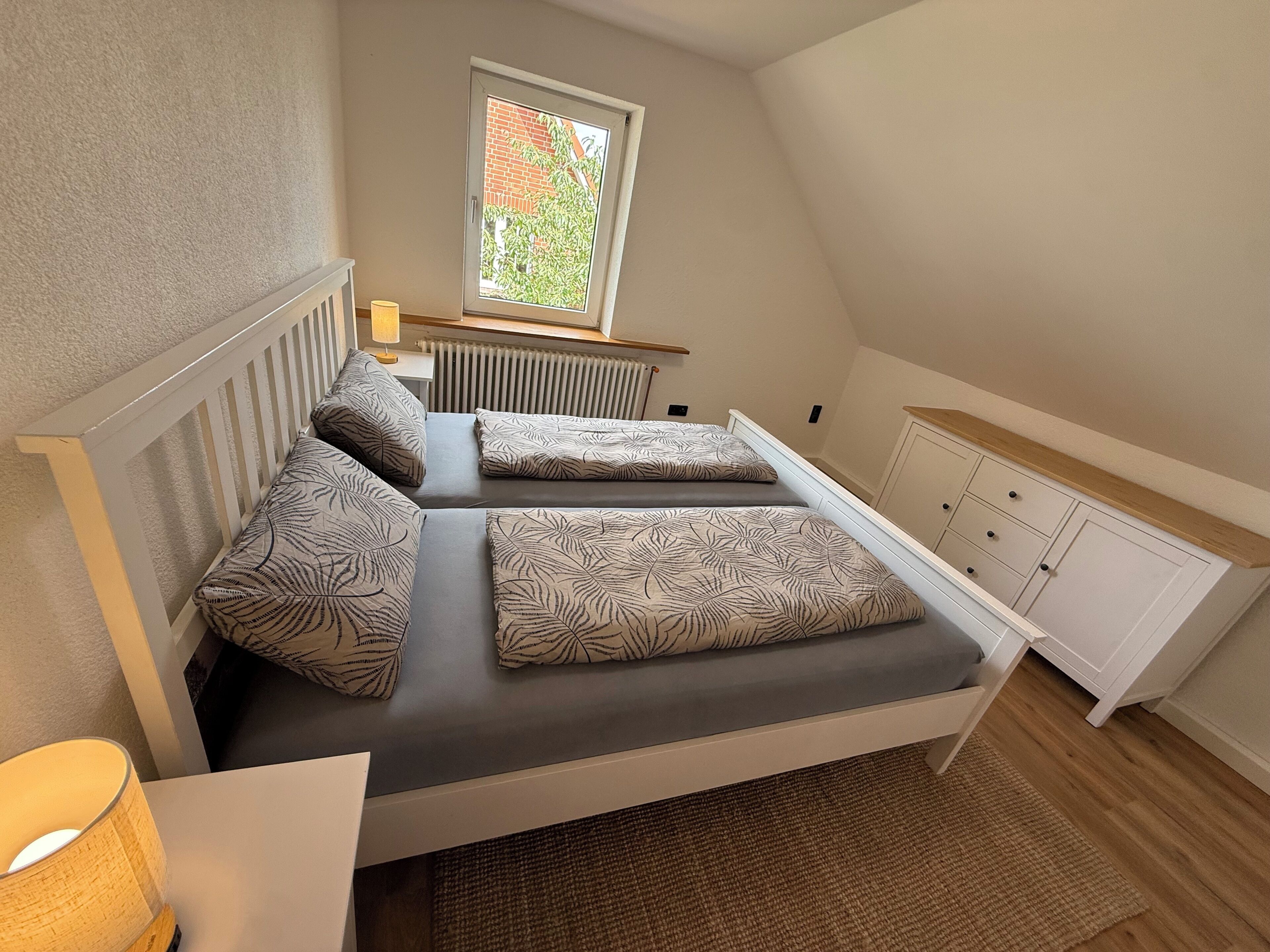 Ein Schlafzimmer mit einem Bett, einem Fenster, einer Heizung und einem Schrank.